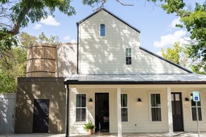 A white building with a black door, windows, and a sign indicating reserved parking. - Cozy Suite with Hot Tub in Fredericksburg (Fredericksburg)