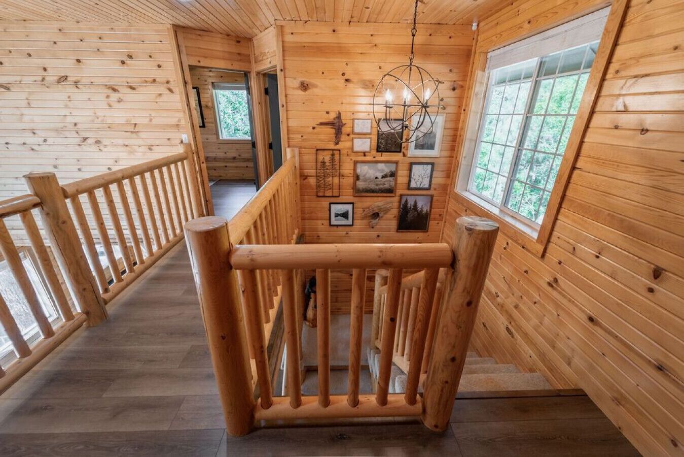 Un intérieur en bois avec un escalier, des rampes d’escalier en bois et des tableaux encadrés accrochés aux murs.