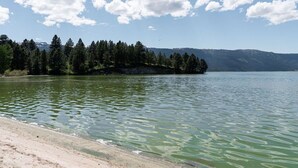 A lake with a sandy beach and a forested island in the background. - Cozy Cabin Close to Lake Cascade w/ Hot Tub (Cascade)