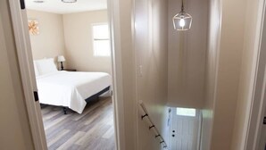 Ein Schlafzimmer mit einem Bett, einem Nachttisch, einer Lampe und einem Fenster.