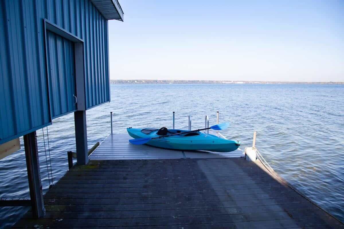 A kayak docked at a wooden pier extending from a blue building over calm water.
