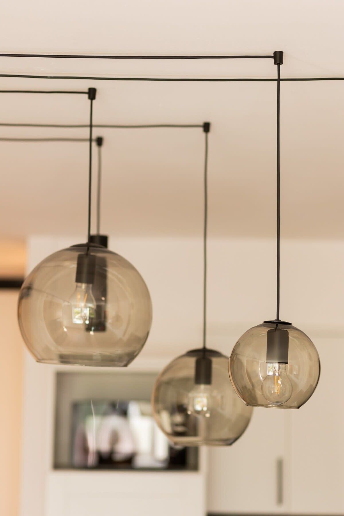 Three pendant lights with clear glass shades hanging from a ceiling with visible electrical wiring.