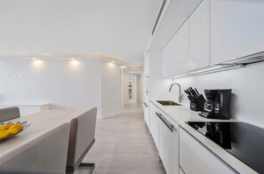 A modern kitchen with white cabinetry, a black coffee machine, and a fruit bowl on the counter. - Ideal Long-Term | Bayviews & Balcony | StayCozy (Miami)