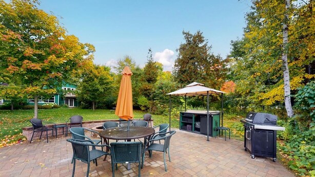 A patio with a table and chairs, a grill, and a covered seating area. - Moon Path on Little Glen (Empire)