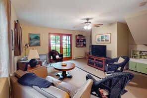 A living room with a sofa, armchairs, a coffee table, a television, and a bookshelf. - Moon Path on Little Glen (Empire)