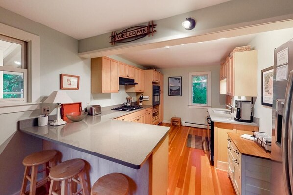 Une cuisine moderne avec un îlot central, des meubles en bois et une pancarte indiquant « BIENVENUE ».