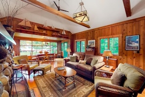L’intérieur chaleureux d’un chalet avec des murs en bois, un coin repas, un canapé et une cheminée.