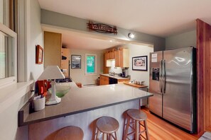 A modern kitchen with a central island, stainless steel appliances, wooden cabinets, and a 'WELCOME' sign. - Moon Path on Little Glen (Empire)