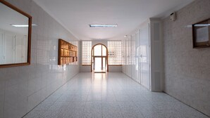 Ein Flur mit Fliesenboden, einem Holzschrank und einem großen Bogenfenster.
