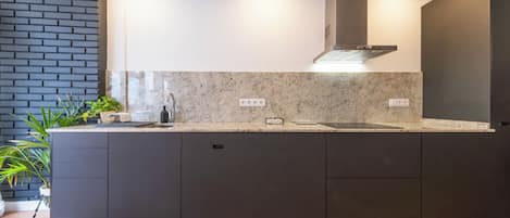 Una cocina moderna con armarios oscuros, encimera de granito y estufa integrada.