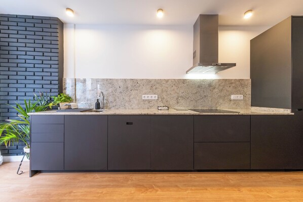 Een moderne keuken met donkere kastjes, een granieten werkblad en een ingebouwd fornuis.