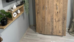 A room with a wooden wardrobe, a mounted television, and a wall-mounted air conditioner. - KAYNARCA HOTEL (Iznik)
