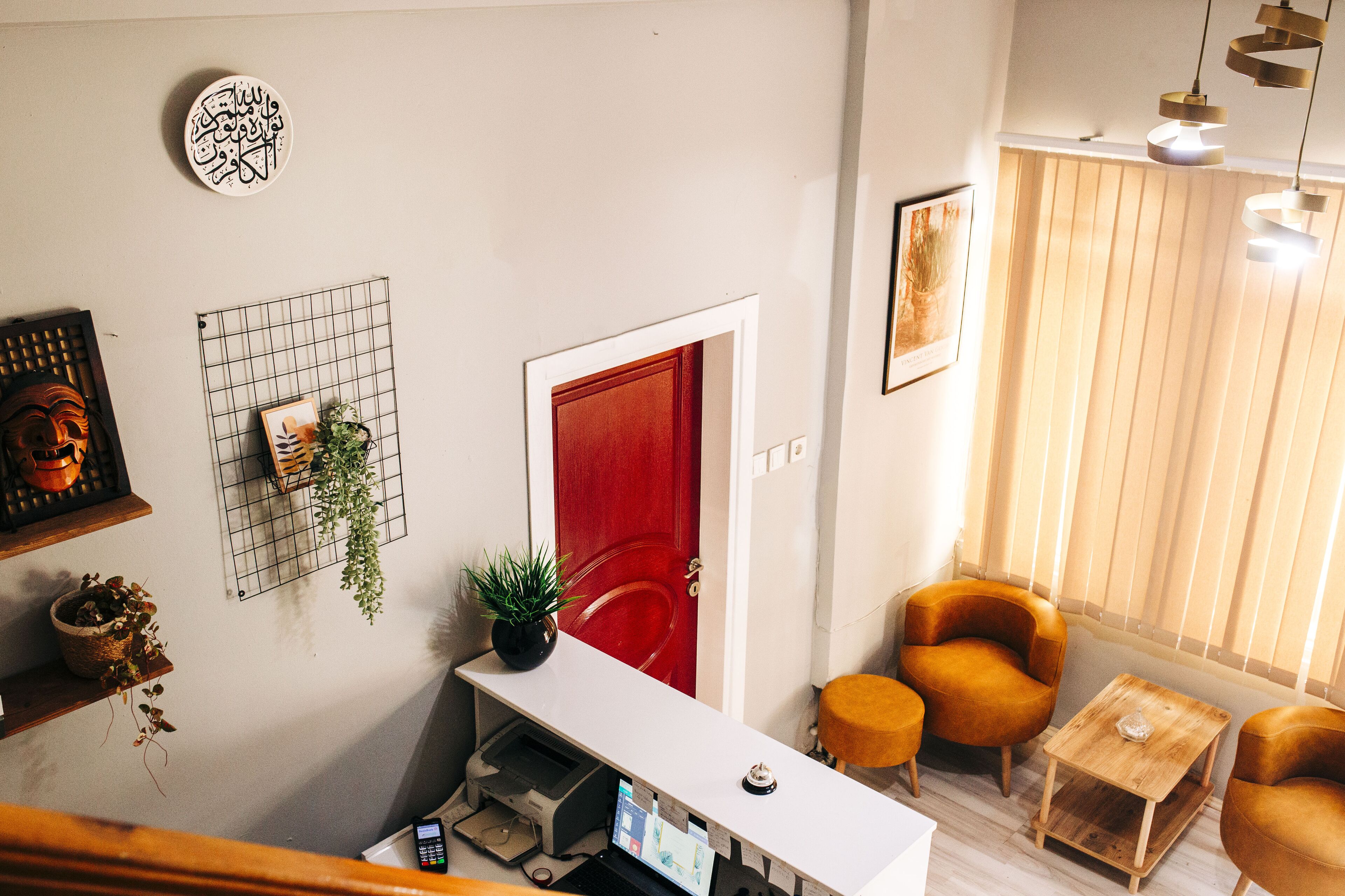 A modern living room with a white console table, a red door, and a seating area with two orange chairs and a small wooden table.