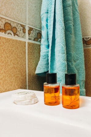 A bathroom with patterned tiles, a white sink, and two bottles of liquid soap. - KAYNARCA HOTEL (Iznik)