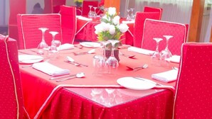 A dining area with red tablecloths, white plates, and clear glassware. - Elanacha Hotel (Arusha)