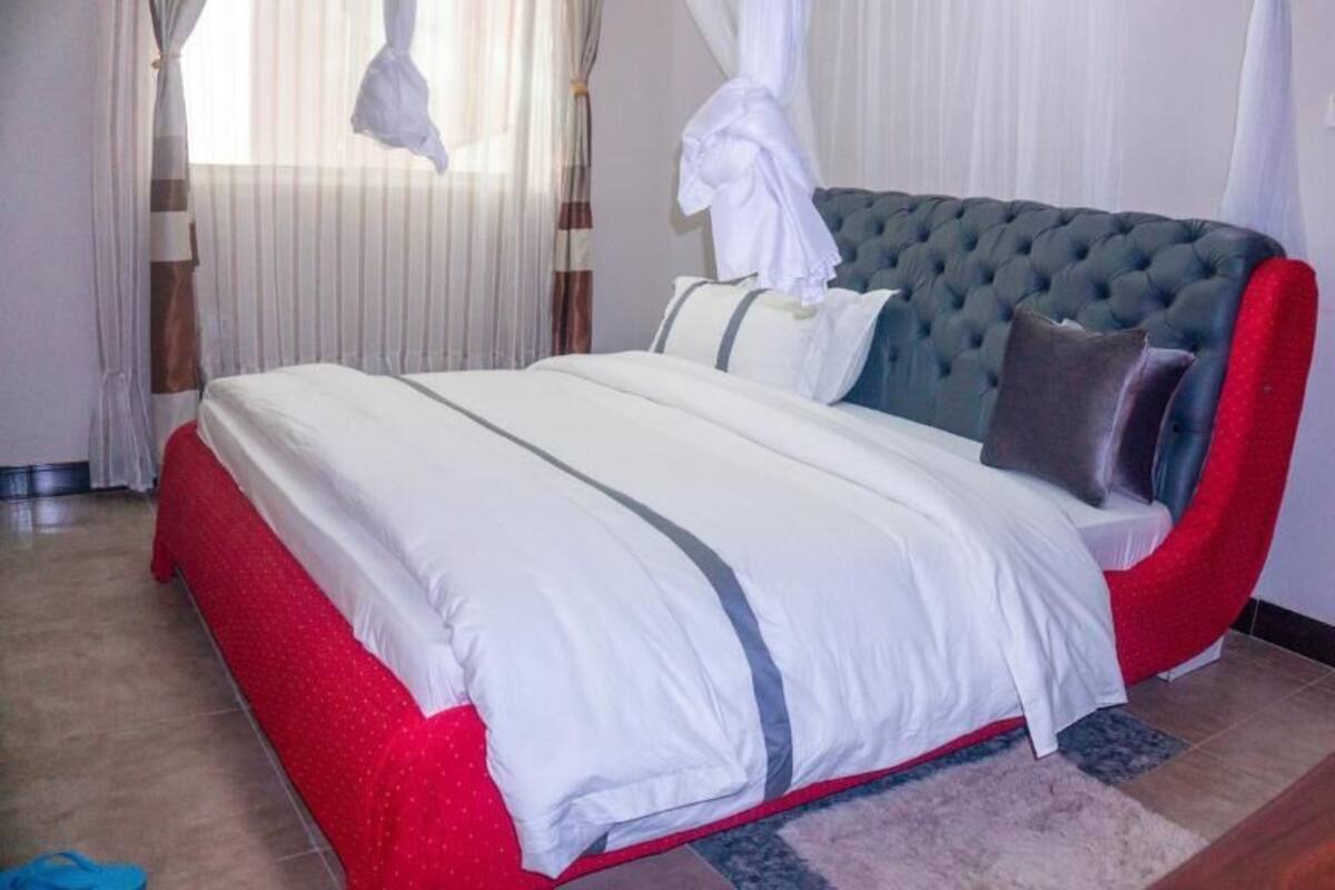 A bedroom with a bed, curtains, and a window.