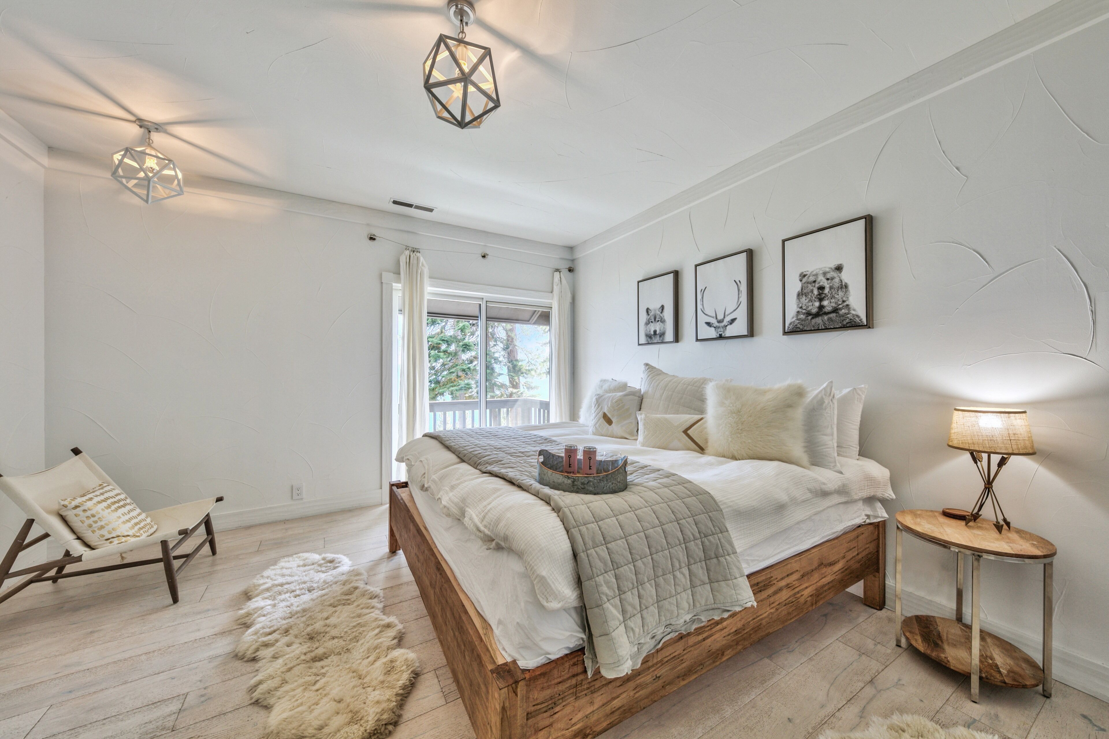 A bedroom with a wooden bed, a chair, a lamp, and wall art.