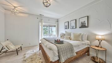 A bedroom with a wooden bed, a chair, a lamp, and wall art.