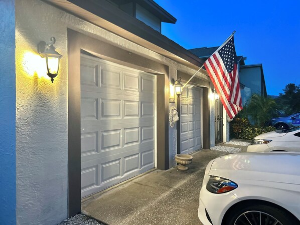 Two-car garage with a decorative lion head emblem on each door, featuring an American flag and a parked vehicle.
