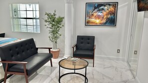 Relax in a serene space with a leather sofa, armchair, and abstract art.