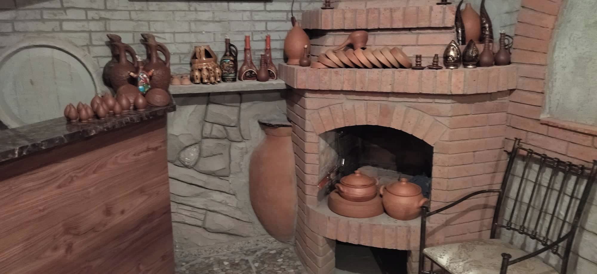 A traditional brick oven with pottery and clay items displayed on shelves above it.