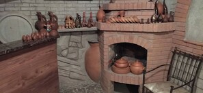 Un horno de ladrillo tradicional con cerámica y elementos de arcilla exhibidos en repisas superiores.