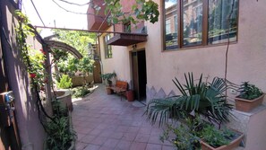 Un pati amb una banca, plantes en testos i una pérgola.