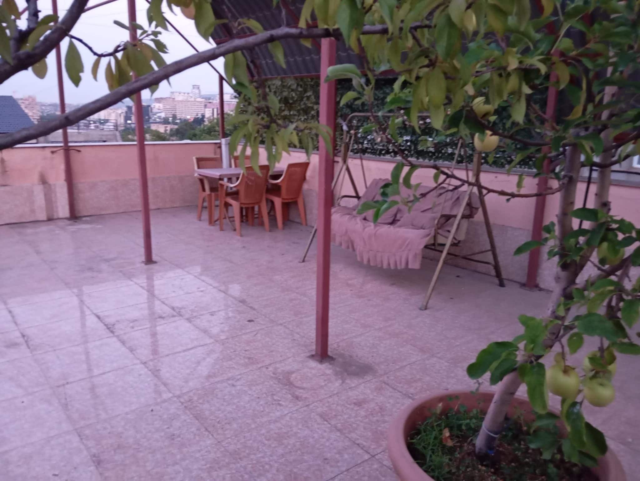 Terrassa al terrat amb taula i cadires, un balancí i una planta en test.