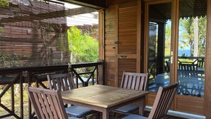 Une terrasse en bois avec une table et des chaises, une lanterne suspendue et une vue sur l’extérieur.