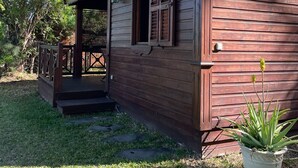 Une cabane en bois avec un porche, une petite terrasse et une plante en pot.
