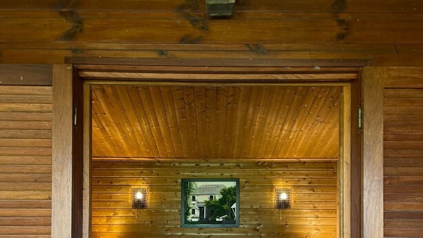 Une chambre dans une cabane en bois, avec un lit, deux lampes de chevet, un tableau encadré au mur et un plafond en bois.