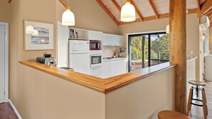 Une cuisine moderne avec des armoires blanches, un plan de travail en bois et des luminaires suspendus.