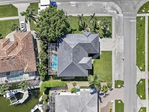 Vista aérea de una propiedad residencial con piscina, muelle y jardín ajardinado.
