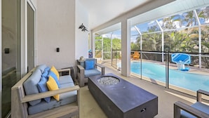 Un espace de détente extérieur moderne, doté d’une piscine, de sièges confortables et d’un foyer.