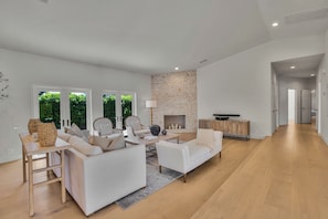 A modern living room with a stone fireplace, white sofas, and a wooden coffee table.
