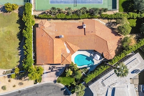 Eine Vogelperspektive auf ein Wohnanwesen mit Swimmingpool, Tennisplatz und einem angelegten Garten.