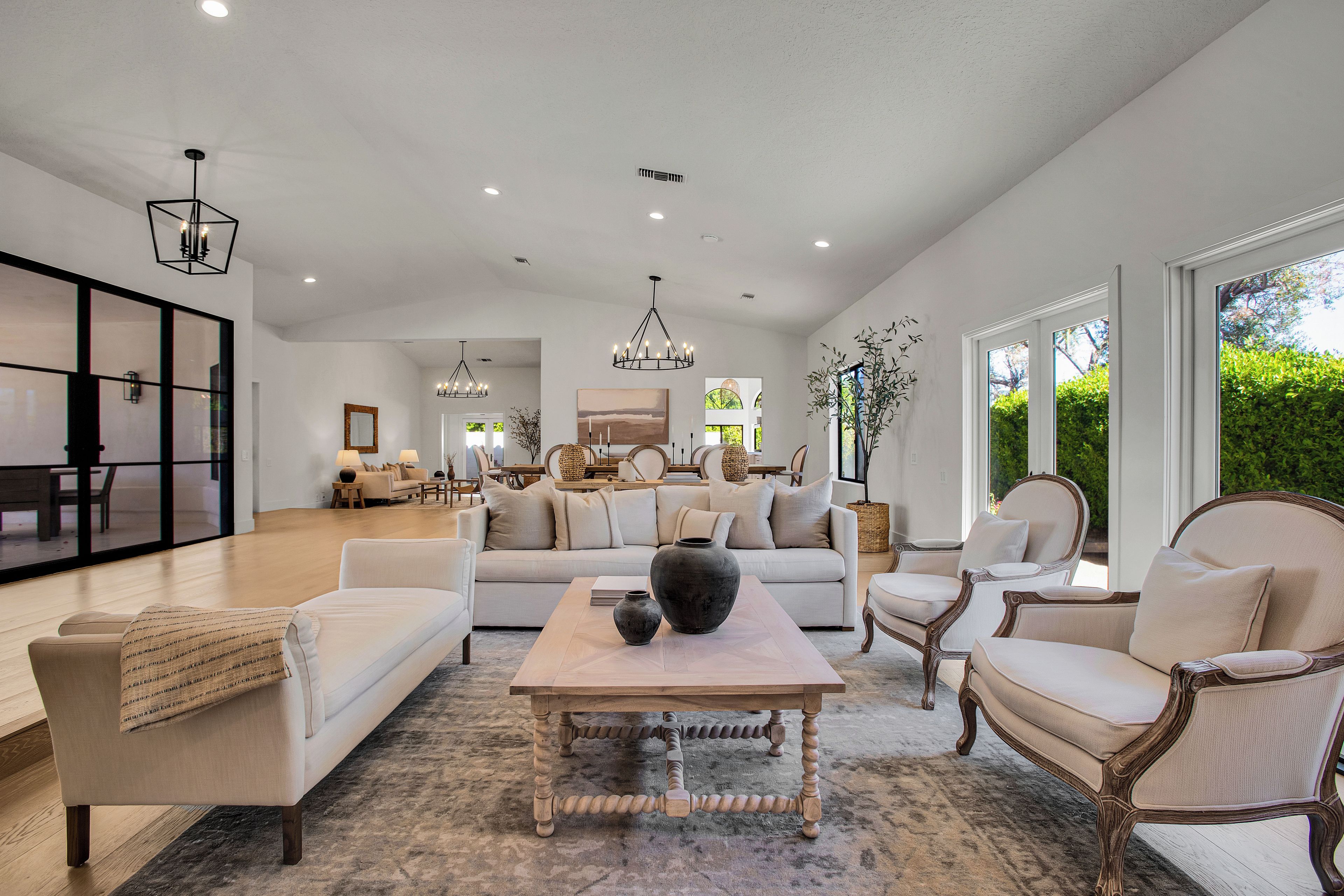A spacious living area with a large sofa, armchairs, a coffee table, and a dining area in the background.
