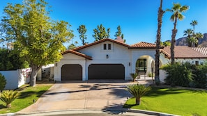A two-story house with a red-tiled roof, a garage, and a well-maintained lawn.