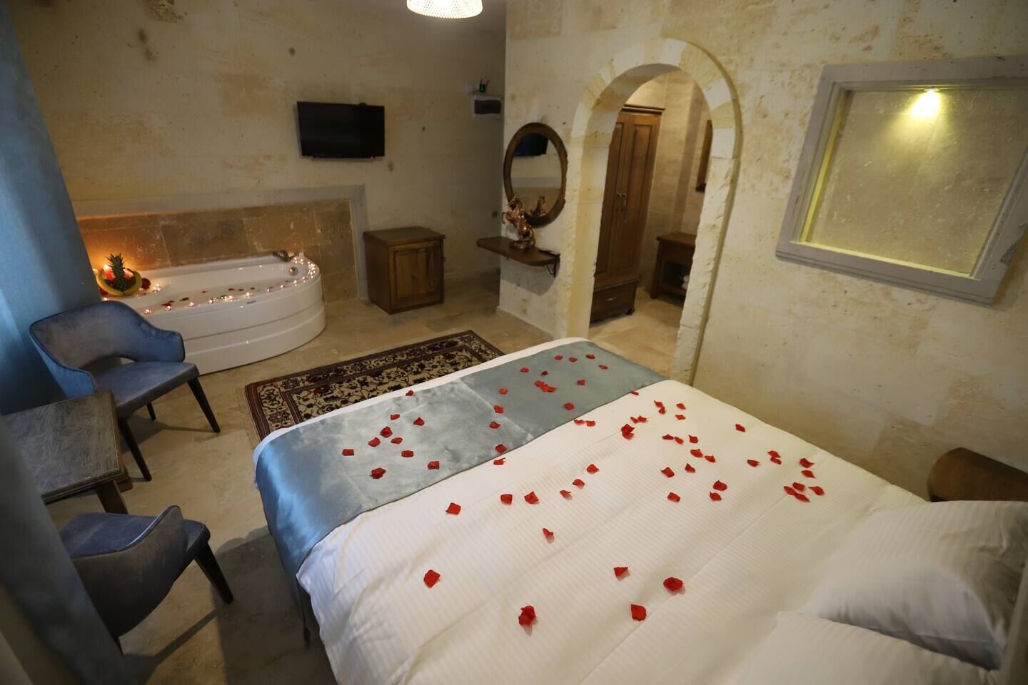 Et hotelværelse med en seng, et opholdsområde med en stol, et badekar og et fjernsyn.