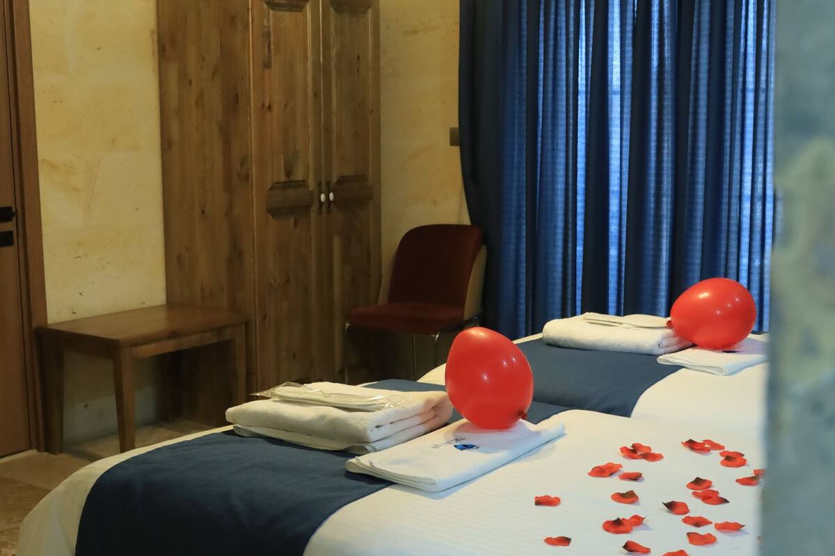 A hotel room with a bed, a wooden wardrobe, a red chair, and a ceiling with decorative lighting.