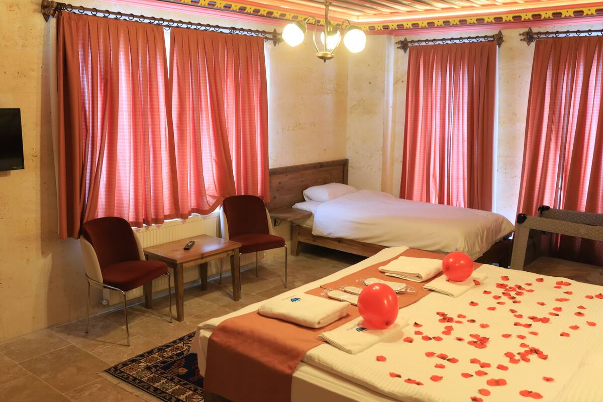 A hotel room with a bed, a desk, two chairs, and a window with curtains.
