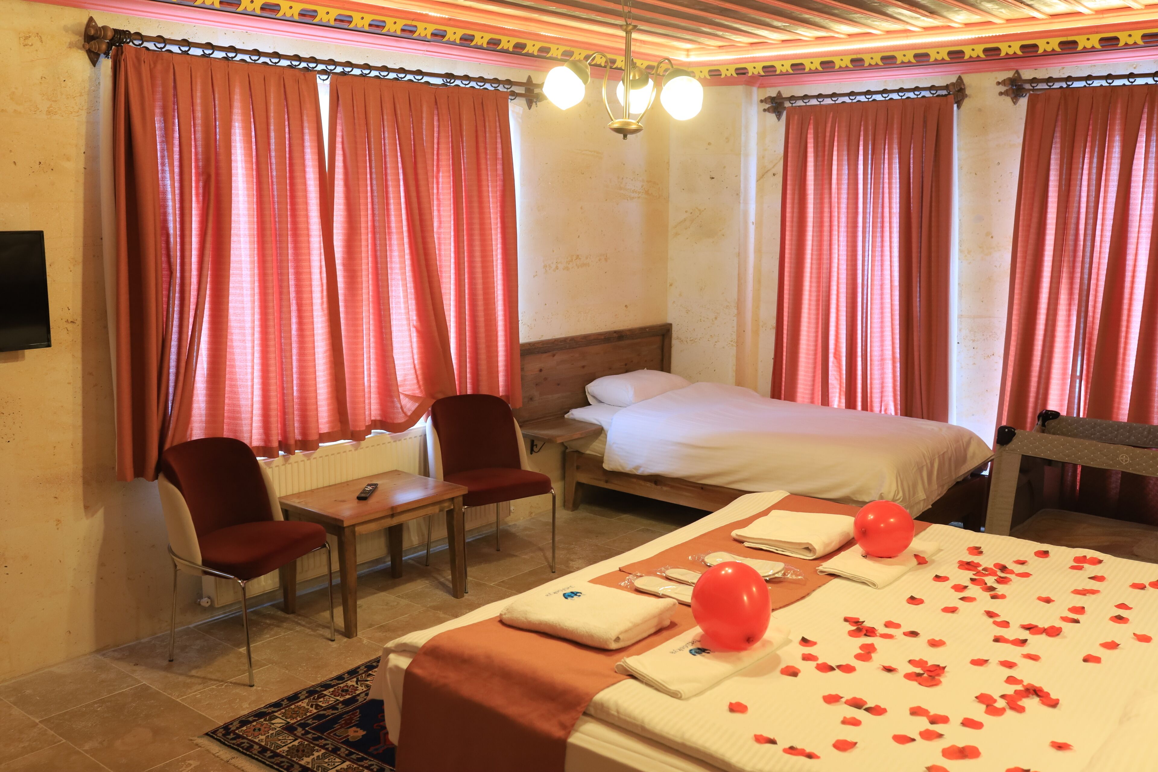 A hotel room with a bed, two chairs, a table, and a television.