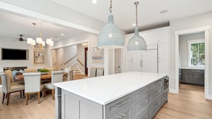 Una cucina moderna con un'isola grande, mobili grigi e illuminazione a sospensione.