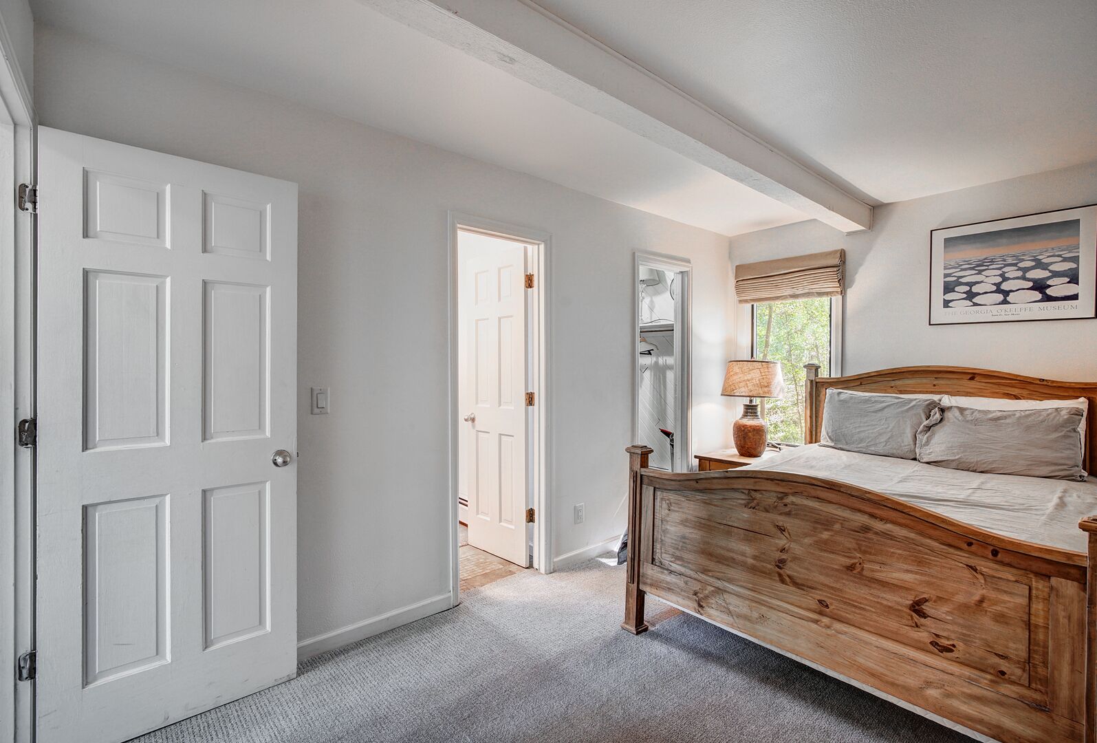 A bedroom with a wooden bed, a nightstand, a lamp, and a framed picture on the wall.