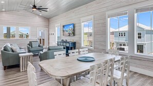 A spacious living room with a large wooden dining table, comfortable seating, and a ceiling fan. - 114 Seven Palms, Sunshine and Flip Flops (Fulton)