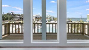 A room with three windows overlooking a beach, a pool, and a view of houses. - 114 Seven Palms, Sunshine and Flip Flops (Fulton)