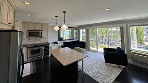 A modern kitchen with stainless steel appliances, a central island, and pendant lighting. - Lakeview condo steps to famous Lake Street, Kirkland (Kirkland)