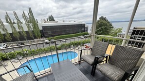 A balcony with a pool, wicker furniture, and a view of the water. - Lakeview condo steps to famous Lake Street, Kirkland (Kirkland)