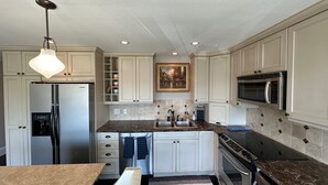 A modern kitchen with white cabinets, a stainless steel refrigerator, a microwave, and a granite countertop. - Lakeview condo steps to famous Lake Street, Kirkland (Kirkland)