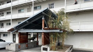 A modern building with a covered entrance, concrete planters with bamboo, and a car parked in front. - Lakeview condo steps to famous Lake Street, Kirkland (Kirkland)